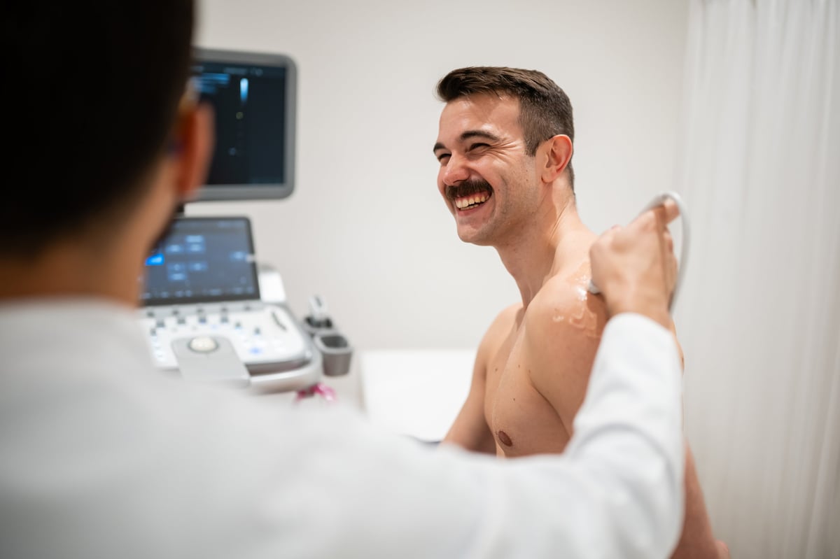 Médico utilizando su equipo de ultrasonido portátil durante la consulta